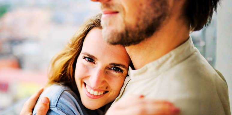 Woman smiling while hugging her partner.