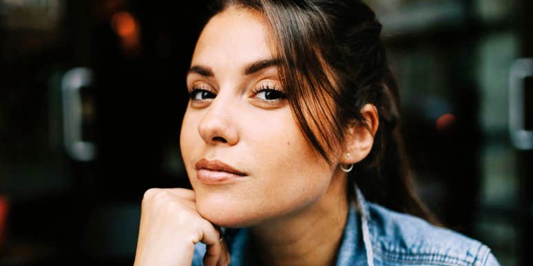 A woman resting her chin on her hand while looking toward the camera.