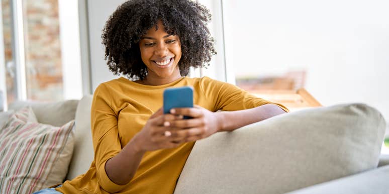 woman on her phone while sitting on couch at home