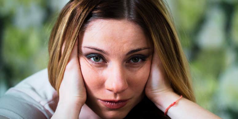 A woman rests her head in her hands while lying down indoors.