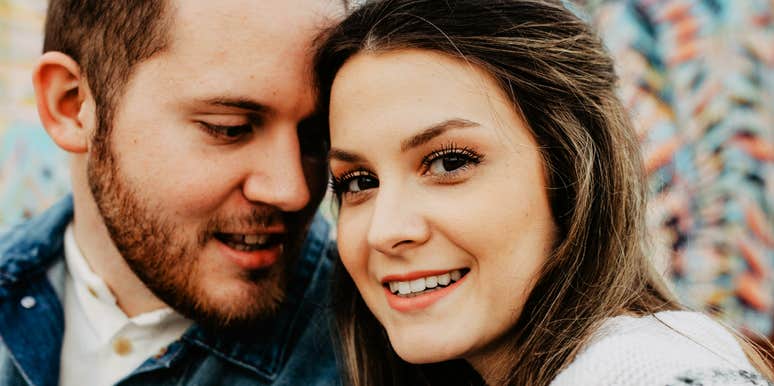 Couple smiling while standing outdoors. 