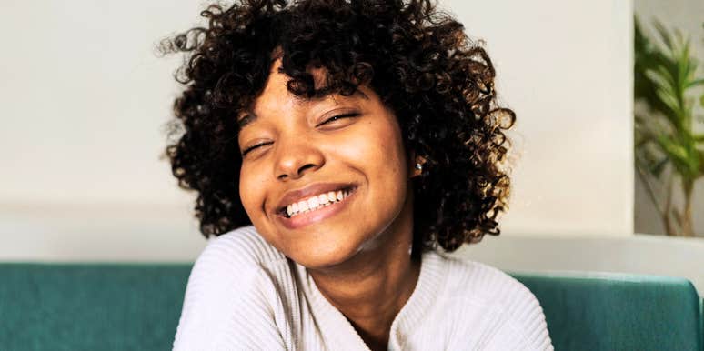 A smiling person sitting indoors on a couch.
