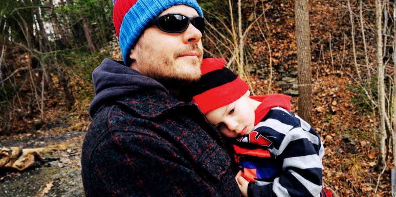 A man holding his young child outdoors during a quiet moment.