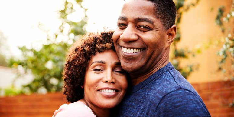 A smiling couple embracing outdoors.