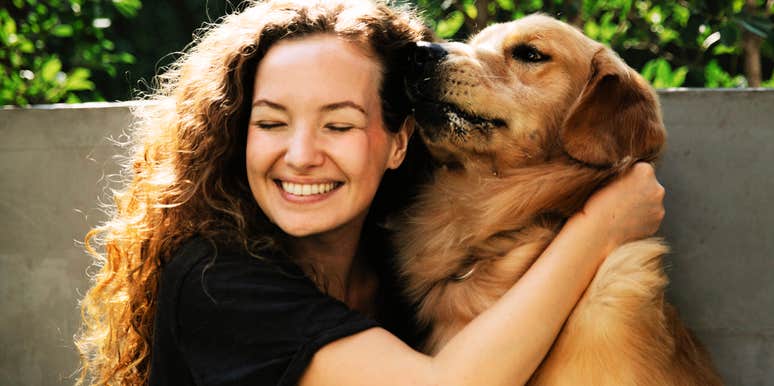 A woman hugging a dog outdoors.