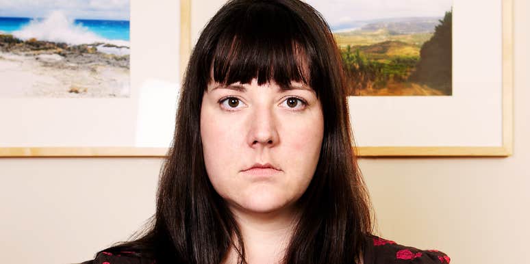 A woman looking straight at the camera while sitting indoors.