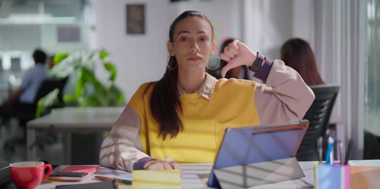 gen z employee giving thumbs down sitting in office