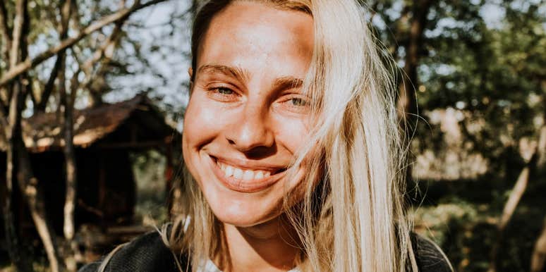 Smiling woman outdoors with trees in the background