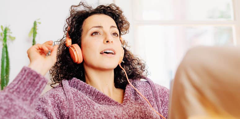 Woman wearing headphones and relaxing indoors near a window.