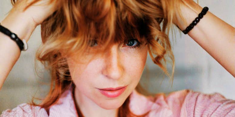 Woman with relaxed expression running her hands through her hair in soft natural light