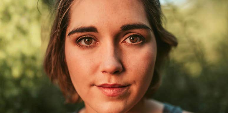 Close-up portrait of a woman outdoors with a calm, reflective expression