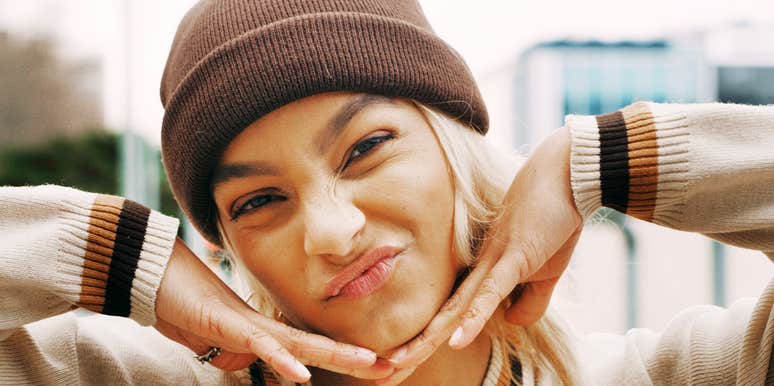 Smiling woman wearing a knit hat posing outdoors.