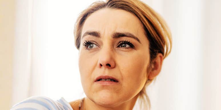 A woman with her hair pulled back looking thoughtfully to the side.