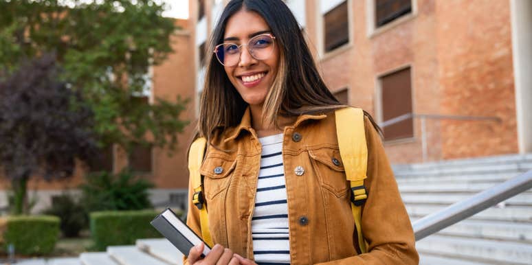 smart female student standing in front of school