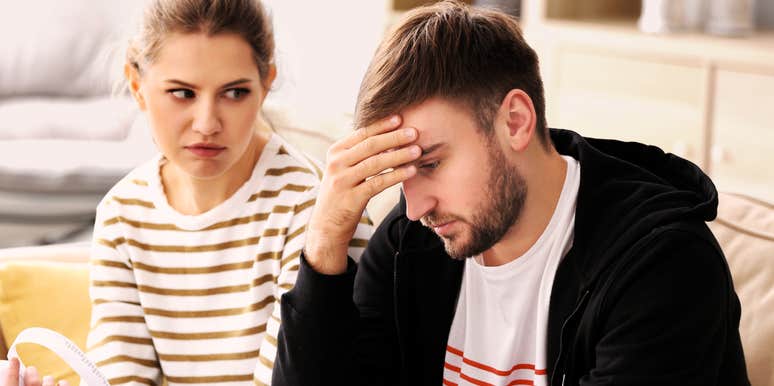 Angry woman looking at her partner, who holds his head in frustration, illustrating arguments that are deeper than surface-level conflicts like chores