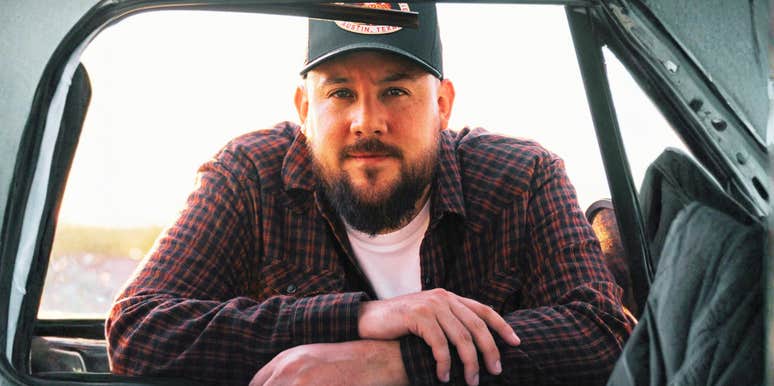 Man leaning against a door window with a serious, distant expression, conveying introspection and emotional withdrawal.