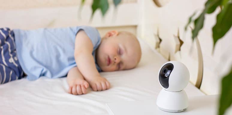 baby sleeping next to baby monitor camera