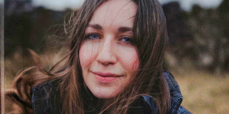 thoughtful woman outdoors with wind-tousled hair and subtle, reflective expression.
