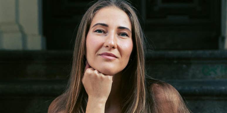 Person with long hair sitting on steps and looking at the camera.