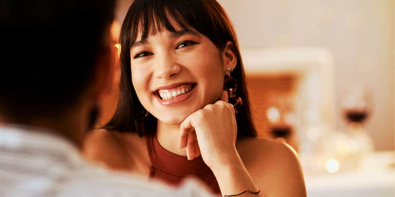 person smiling at someone across a table in a softly lit indoor setting