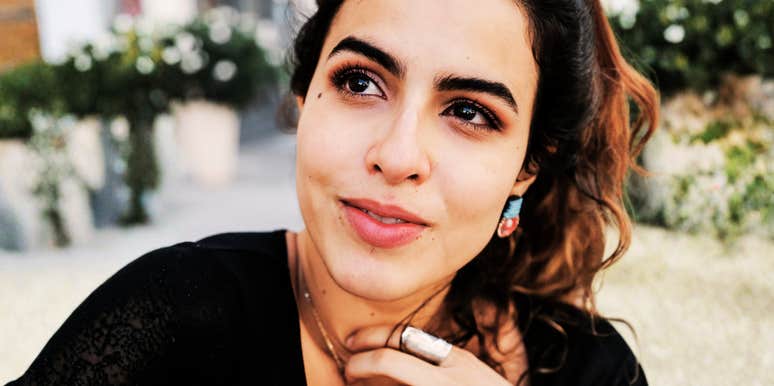 Close-up portrait of a person with dark hair wearing a black top outdoors