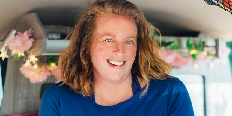 Young woman sitting on a park bench, resting her face in her hands with a pensive, melancholic expression, appearing lost in thought.