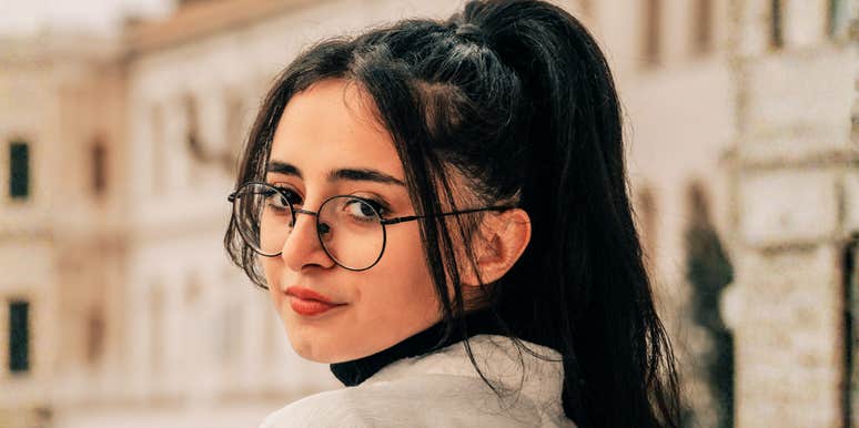 woman looking back with a guarded, observant expression