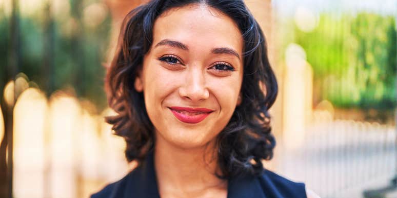 Woman smiling at the camera outdoors with a softly blurred background