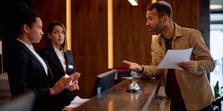 guest arguing with hotel workers behind desk