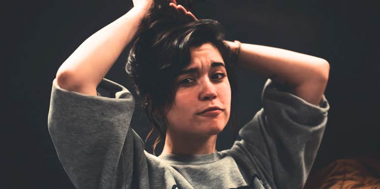 Woman fixing her hair looking confused.