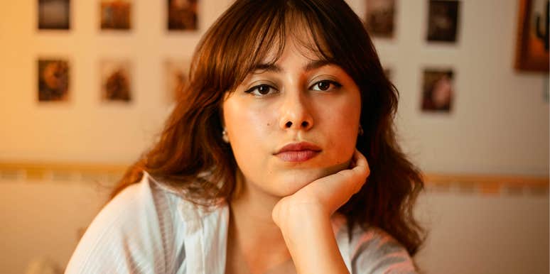 serious young woman resting her chin on her hand in warm indoor light