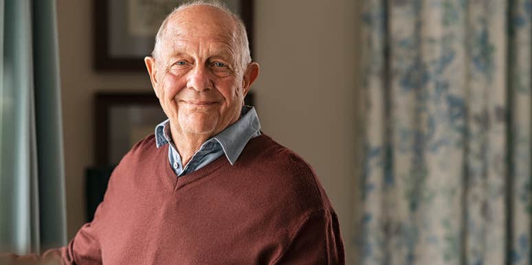 older man standing by window at home