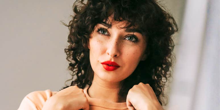 A charming woman thoughtfully choosing a outfit to wear out, illustrating the 'one thing you can control'—your immediate environment and personal rituals—when the future feels uncertain. 