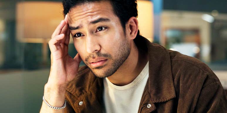 A man at his office desk with his hand on his head, illustrating the physical exhaustion and mental load associated with chronic workplace burnout triggers.