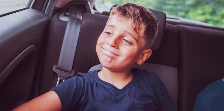 A happy young boy in a car seat, capturing the 'unfiltered joy' and high-spirited nature of raising boys and the long-term meaning behind the chaos.