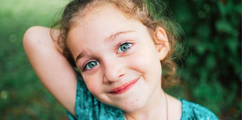 A young bright-eyed girl outside, capturing the 'growth mindset' and curiosity that experts say are more important than academic performance.