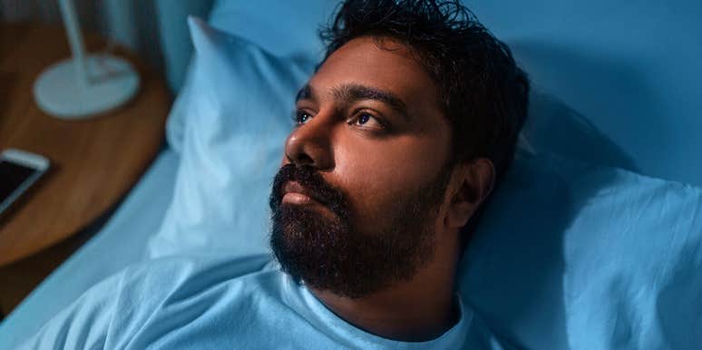 stressed and burned out man lying awake in bed anxious