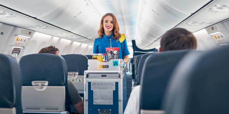 flight attendant pushing down cart on plane
