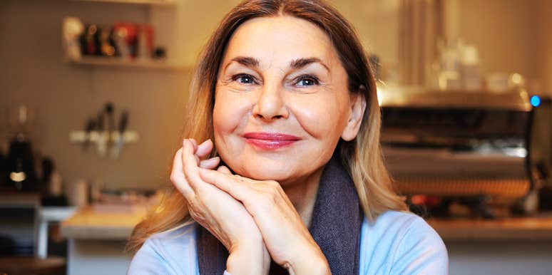A joyful woman enjoying a quiet moment alone at a cozy cafe, representing the quiet strength and independence that defines genuine self-confidence.
