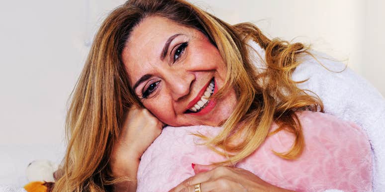 A woman in her fifties enjoying a quiet morning in a bathrobe, representing the 'individualized rest' and emotional health found in modern sleep arrangements.