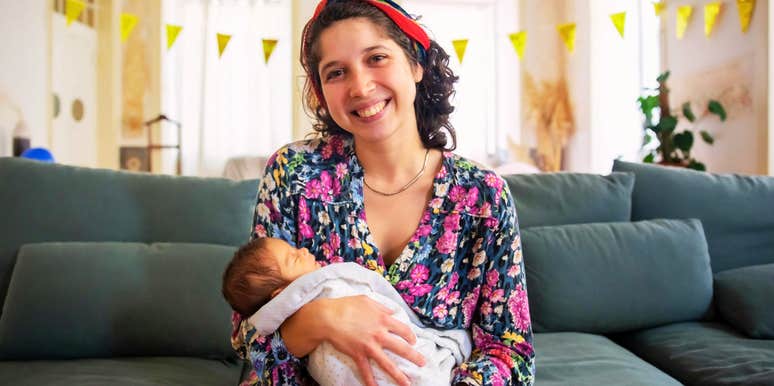 Woman gently holding a newborn baby, illustrating the calming physiological and psychological benefits of physical touch and infant bonding.