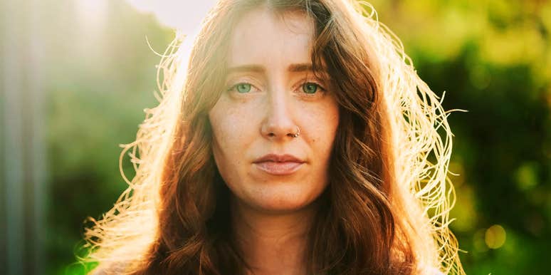 A woman with red hair looking directly at the camera with a neutral, pensive expression, illustrating the 'internal resistance' and psychological reasons people struggle to change their lives.