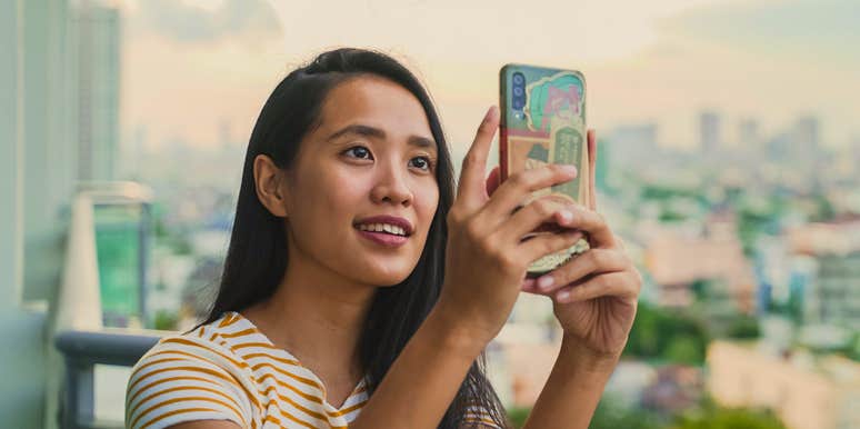 young woman on a balcony taking pictures of the sky when it looks beautiful