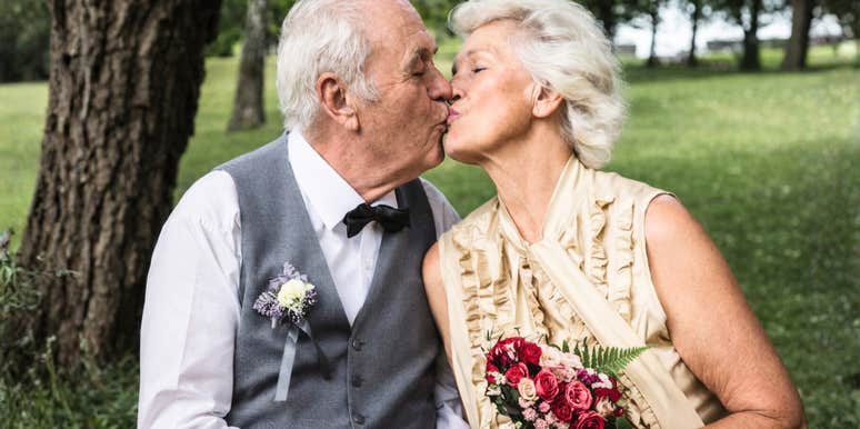 A joyful newlywed elderly couple smiling together, celebrating a historic wedding ceremony held on the groom's 100th birthday.