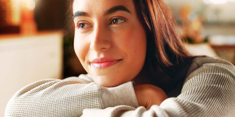 A woman in a living room looking contemplative and calm; a visual representation of trauma recovery and the positive self-talk habits that support long-term wellness.