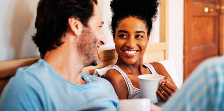 A smiling man and woman bonding over morning coffee in bed; illustrating the powerful impact of consistent, small connection rituals on long-term relationship stability.