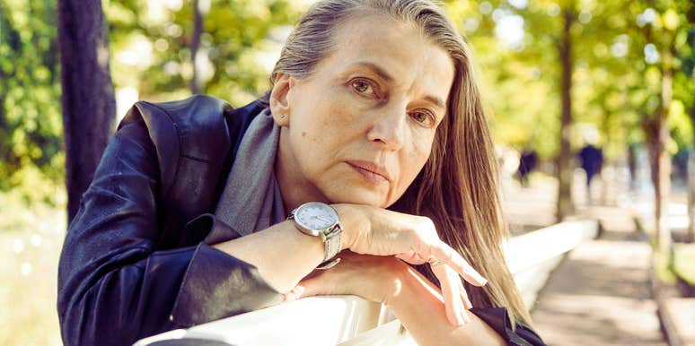 A portrait of a mature woman in a moment of physical reflection, representing the 'silent symptoms' of gut dysbiosis and metabolic shifts in later life.