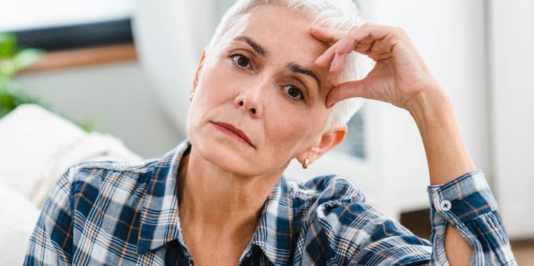 A mature woman with her hand on her head looking pensive, illustrating the 'relational fatigue' and emotional distance often felt in long-term marriages.