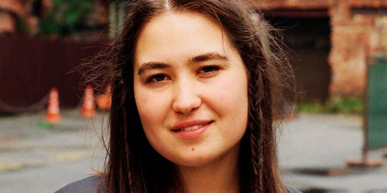 A woman standing in front of an old building, capturing the quiet triumph of someone overcoming social anxiety to finally step back into the world.