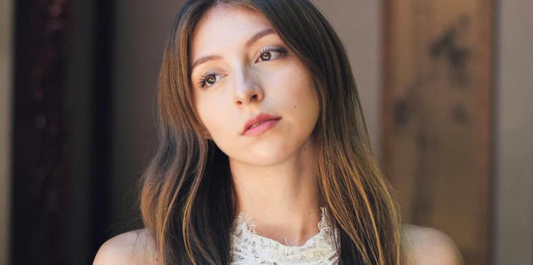 A close-up portrait of a woman with a somber, pensive gaze; illustrating the silent resignation and quiet unhappiness behind the everyday phrases used in failing relationships.